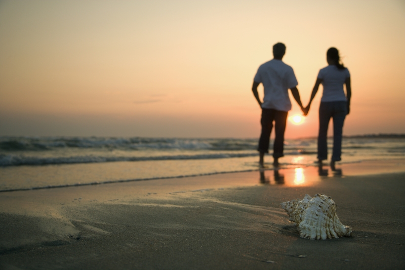 ett par som håller händer på stranden